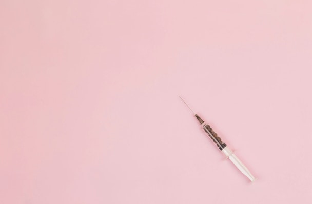 A syringe against a pink background A syringe against a pink background