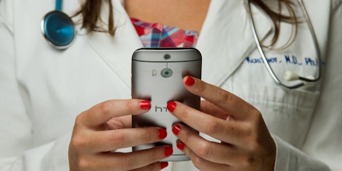 A doctor wearing a stethoscope uses a handheld device A doctor wearing a stethoscope uses a handheld device