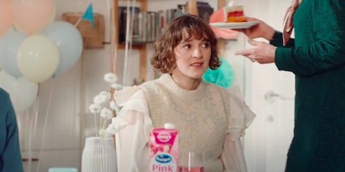 A woman sits at a table at a party with a carton of juice in front of her A woman sits at a table at a party with a carton of juice in front of her
