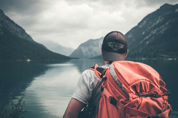 A man with a backpack looking out over a lake A man with a backpack looking out over a lake