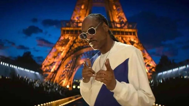 Snoop Dogg holdign a microphone and giving the peace sign with his fingers Snoop Dogg holdign a microphone and giving the peace sign with his fingers