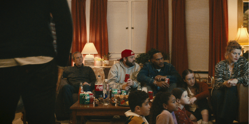People watching TV with multiple The Coca-Cola Company products on the table People watching TV with multiple The Coca-Cola Company products on the table