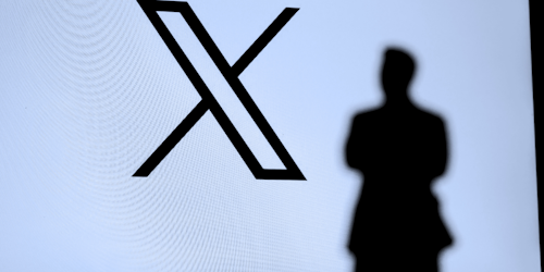 X app logo with man's shadow in front of it X app logo with man's shadow in front of it
