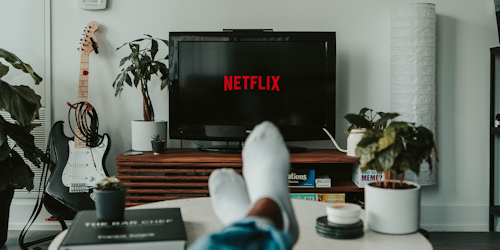 Netflix on TV screen with man's feet in foreground Netflix on TV screen with man's feet in foreground